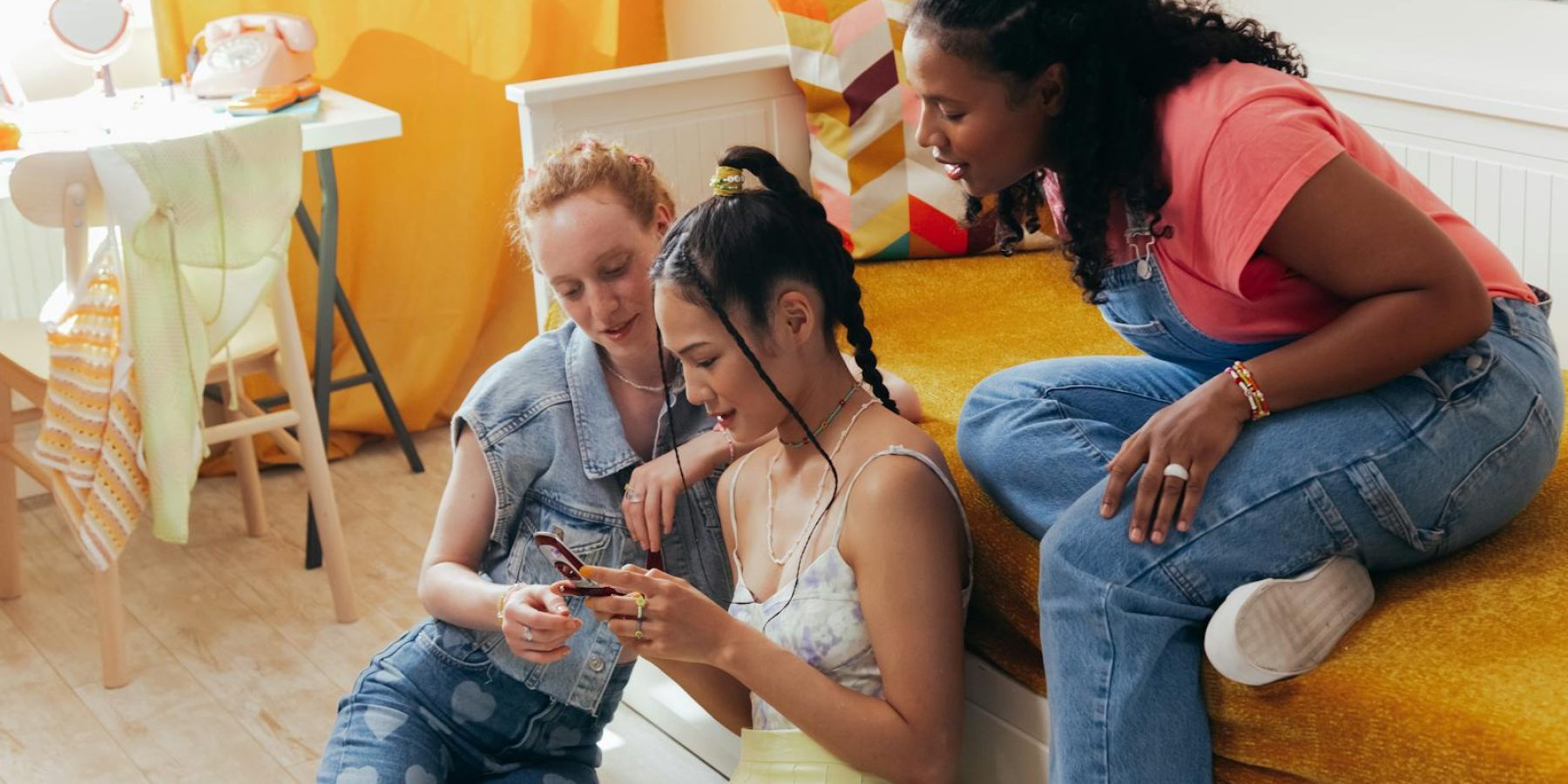 Three diverse teenagers sharing fun moments in a cozy bedroom.